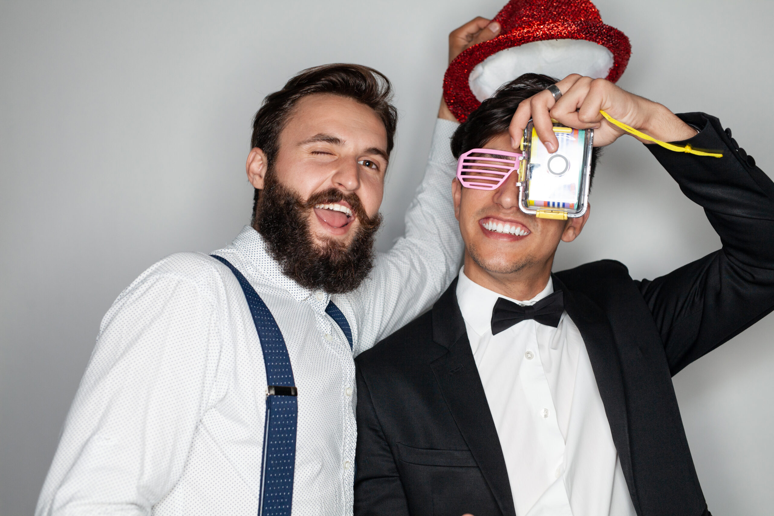 Groomsmen laughing with photo booth props at a wedding reception